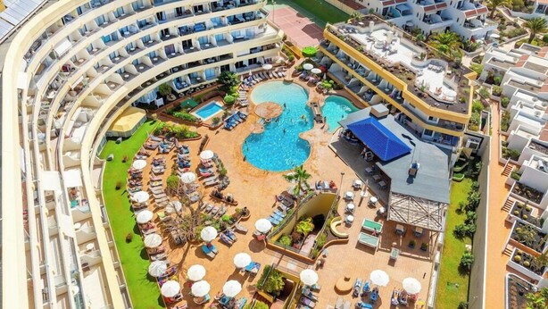 A multi-story hotel with a central swimming pool, outdoor lounge areas, and a curved building structure. - Santa Maria Aparthotel (Adeje)