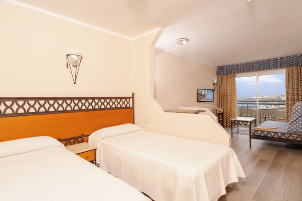 A hotel room with two beds, a desk, a chair, and a balcony with a view. - Santa Maria Aparthotel (Adeje)