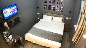 A modern hotel room with a large bed, a desk with a computer, a flat-screen TV, and a wall decorated with photos. - Soso Hostel (Hong Kong)