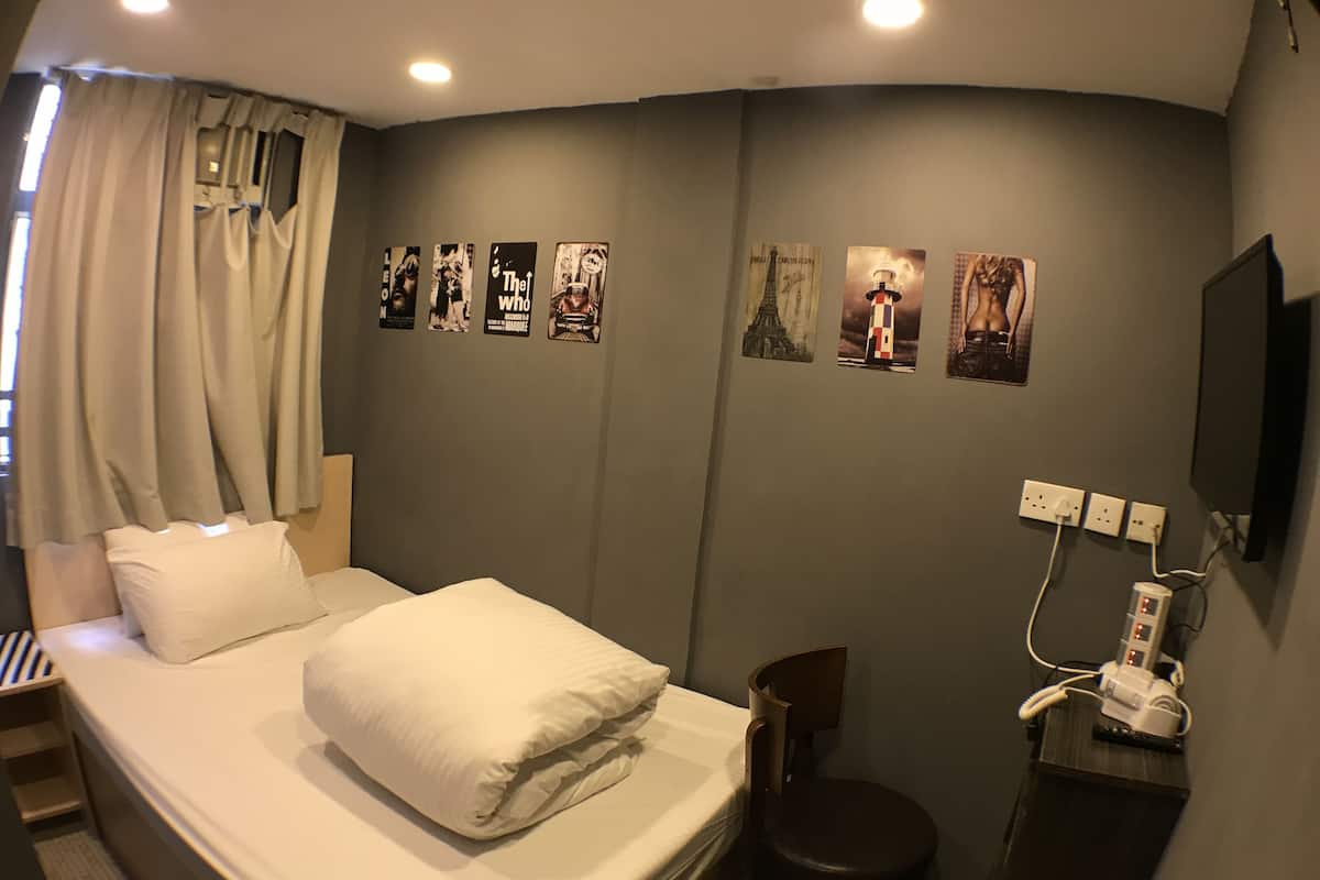 A hotel room with a bed, a chair, a desk, and a wall with pictures.