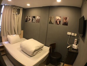 A hotel room with a bed, a chair, a desk, and a wall with pictures.