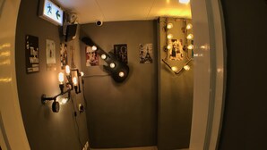 A hallway with a wall-mounted light fixture, a door with a sign, and a patterned floor. - Soso Hostel (Hong Kong)