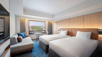 Habitación de hotel con dos camas, un sofá, una mesita y vistas a la ciudad.