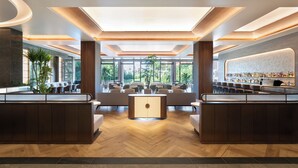 A modern lobby with a central seating area, a bar with a variety of bottles, and large windows offering a view of greenery. - Okinawa Harborview Hotel (Naha)
