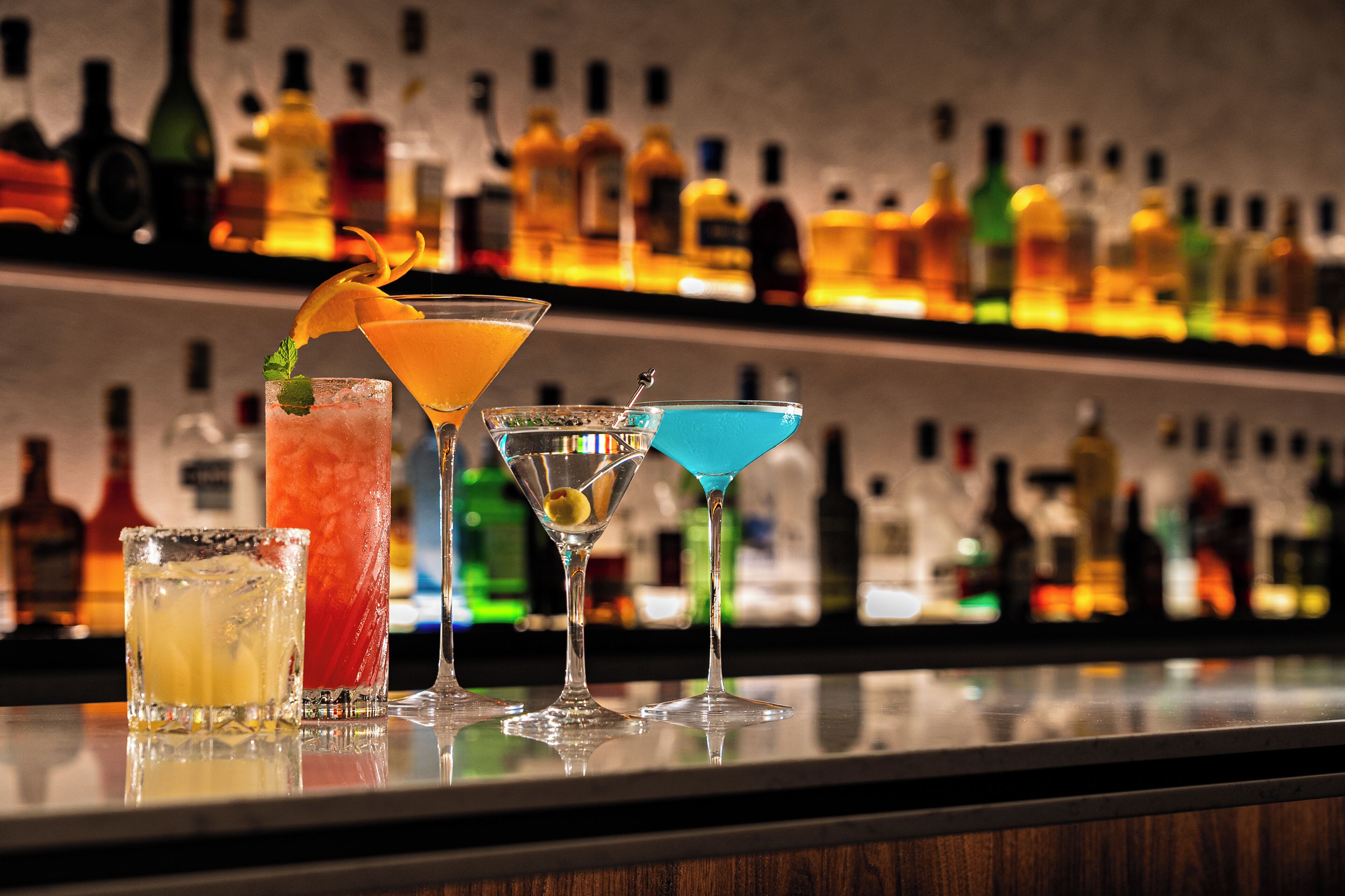 A bar with various cocktails and bottles in the background.