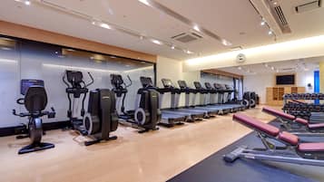 A gym with multiple treadmills, elliptical machines, and weight benches.