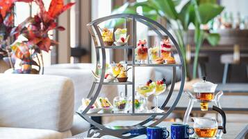 A tea service set with a tiered display stand, a blue cup, and a teapot on a table.