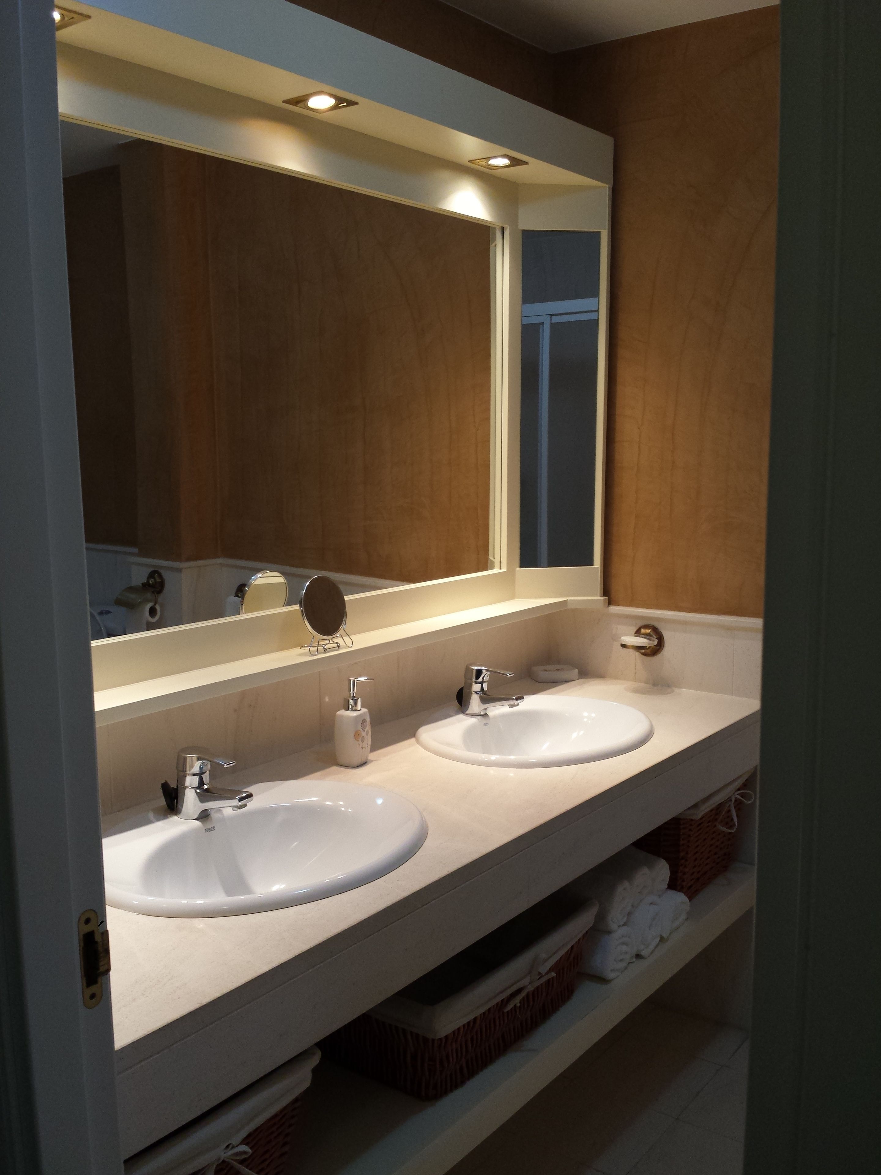 Een badkamer met twee wasbakken, een spiegel en een plank met handdoeken.