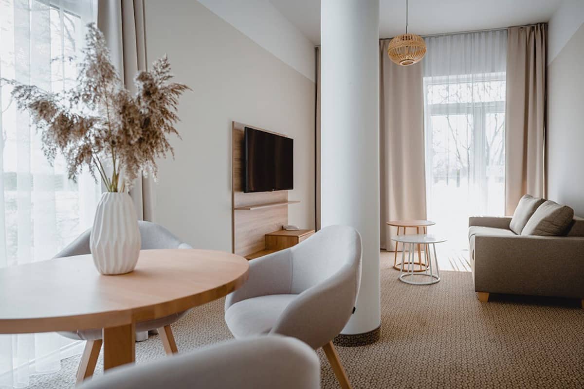 Ein modernes Wohnzimmer mit einem runden Holztisch, einer Couch und einem an der Wand befestigten Fernseher.