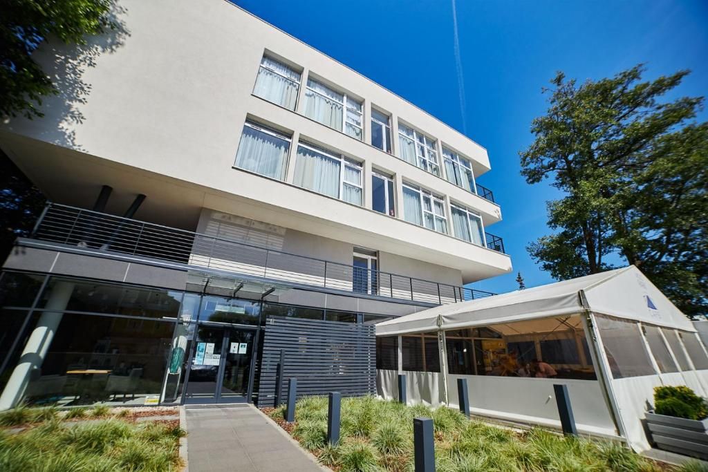 A modern building with a flat facade, large windows, and a covered outdoor area.