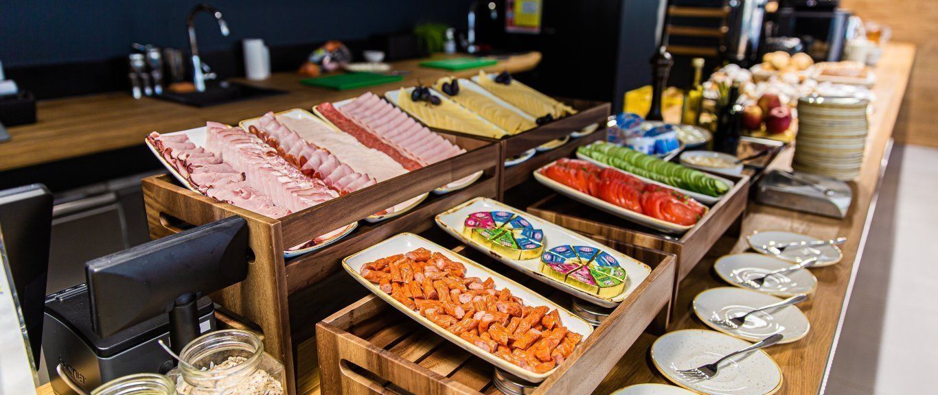 Un bufé con diversos alimentos, incluyendo carnes, quesos y vegetales.