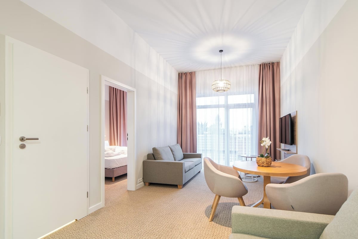 Ein modernes Hotelzimmer mit einer Couch, einem Esstisch und einem Fernseher.