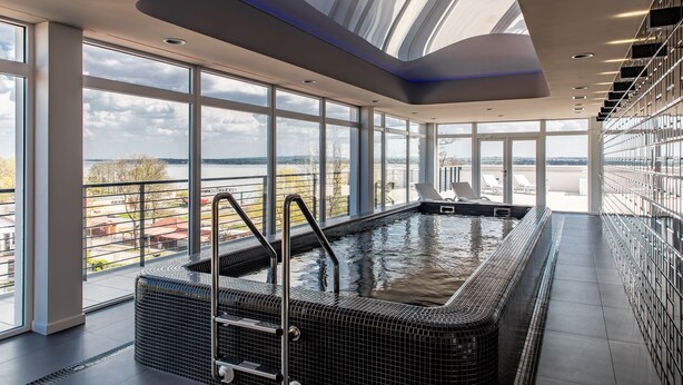 Une piscine intérieure moderne avec vue sur le paysage urbain et une grande verrière au-dessus.