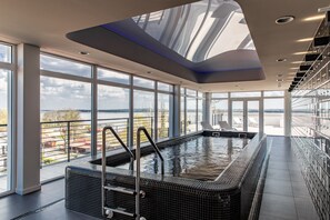 En moderne indendørs swimmingpool med udsigt over bybilledet og et stort ovenlys.