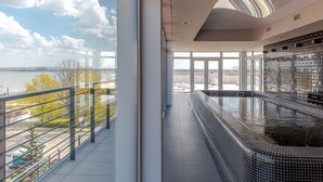 Une piscine intérieure moderne avec vue sur une rivière et des arbres.