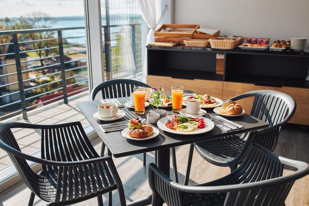A breakfast table with plates of food, glasses of orange juice, and a laptop.