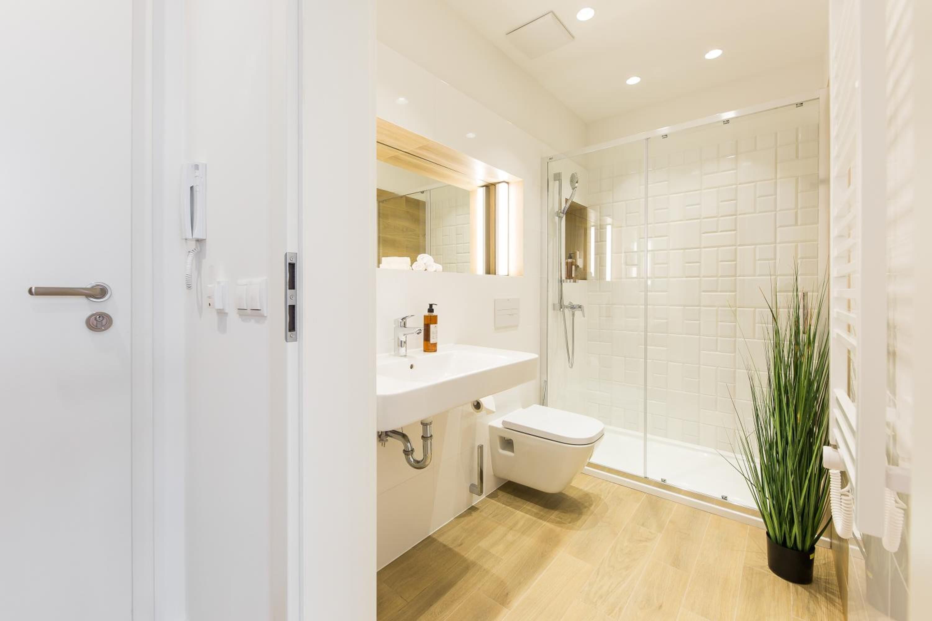 Un baño moderno con lavamanos, inodoro y ducha blancos.