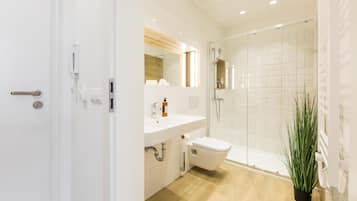 Un baño moderno con lavamanos, inodoro y ducha blancos.