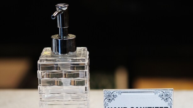 A hand sanitizer bottle with a pump dispenser and a sign labeled "HAND SANITIZER".