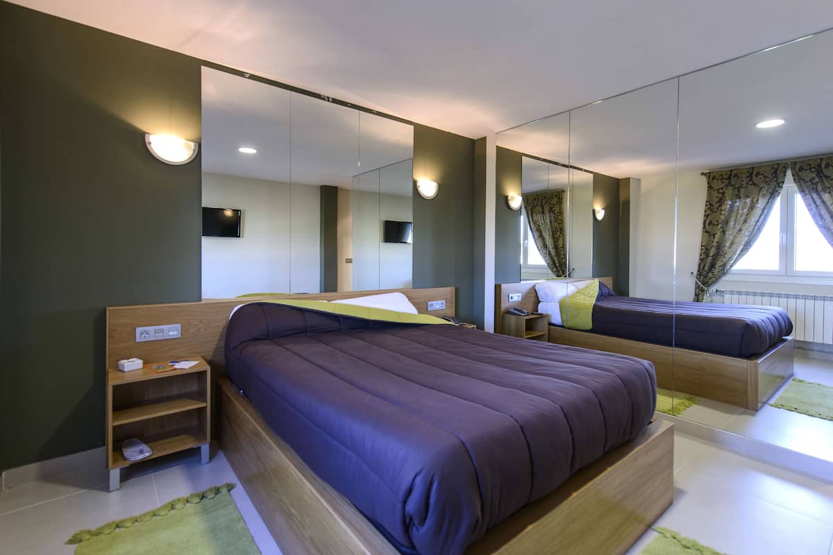 Un dormitorio moderno con dos camas, estanterías integradas, un televisor de pantalla plana y un espejo grande.