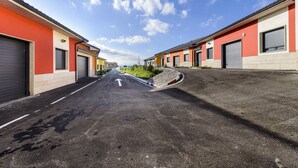 A street with buildings on both sides, a clear sky, and a road with a white arrow indicating direction. - Motel Cancún Avilés (Gozon)
