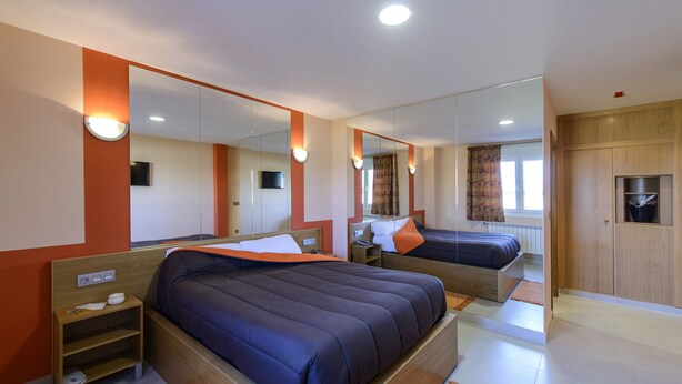 A hotel room with two beds, a large mirror, and a wardrobe. - Motel Cancún Avilés (Gozon)
