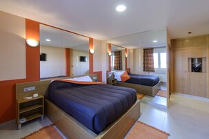 Una habitación de hotel con dos camas, un espejo grande y un armario.
