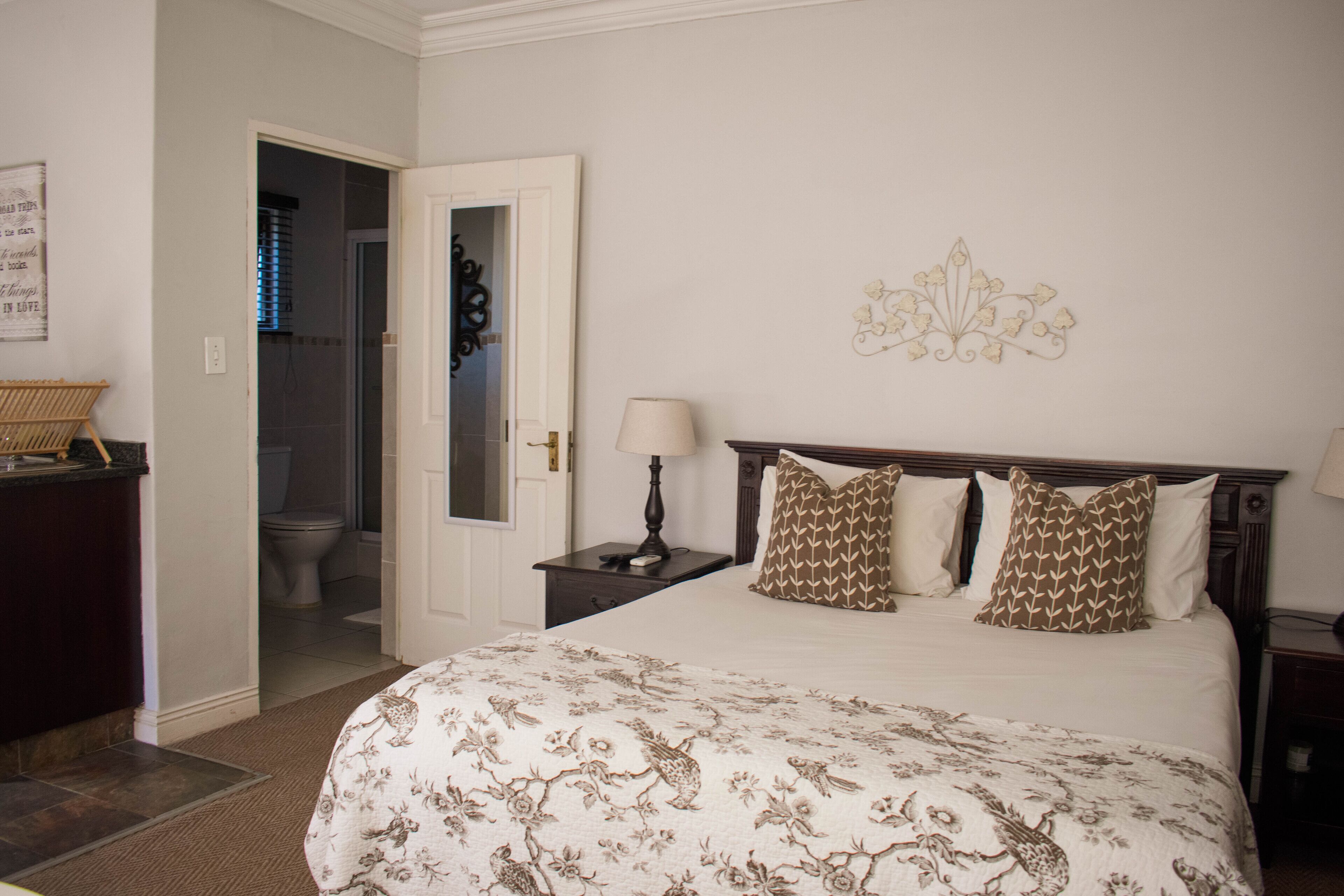 Une chambre d’hôtel avec un grand lit, une table de chevet avec une lampe, une tête de lit en bois et un élément décoratif mural.