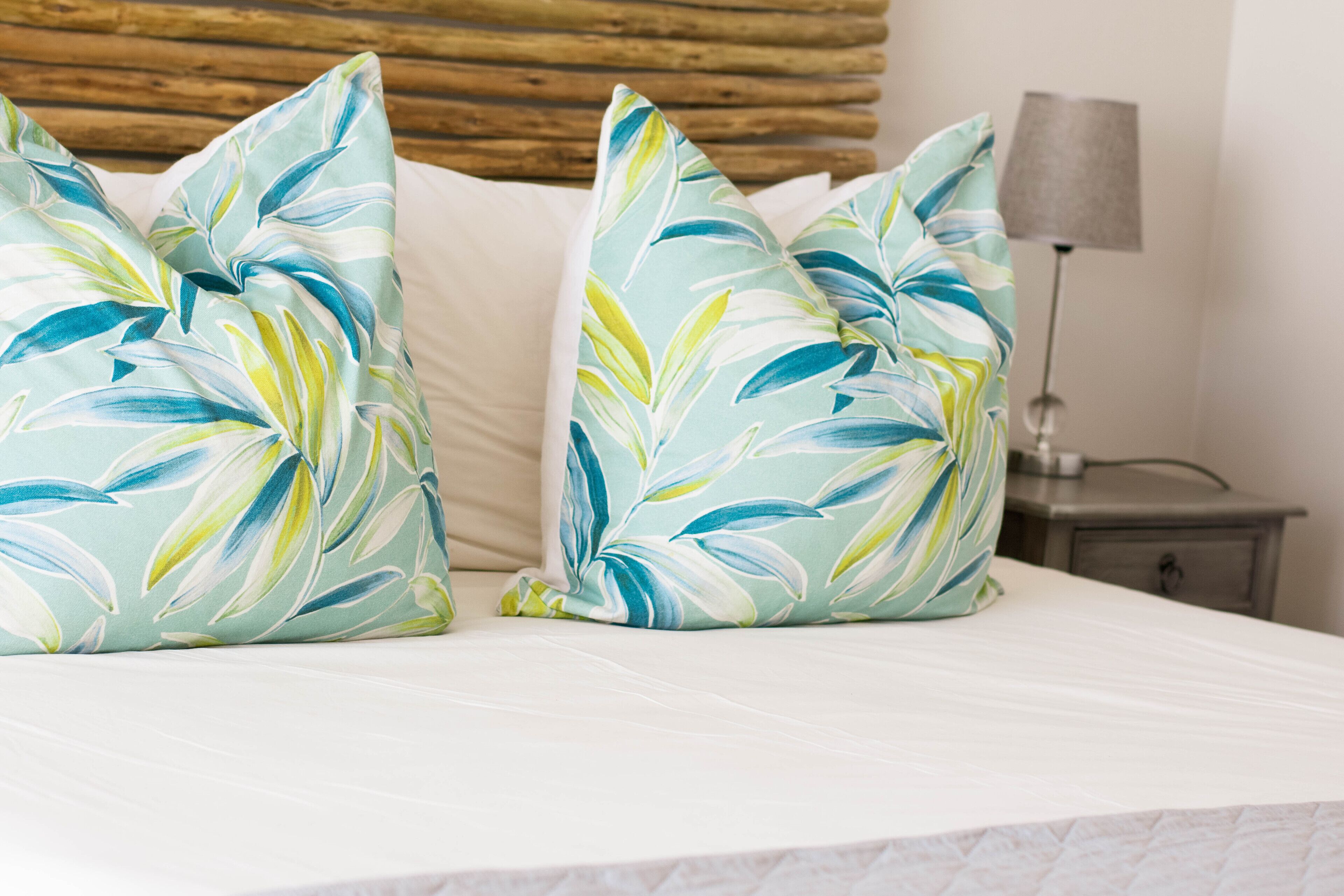 A bed with two decorative pillows and a bedside lamp.