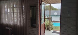 A room with a view of a swimming pool through a glass door.