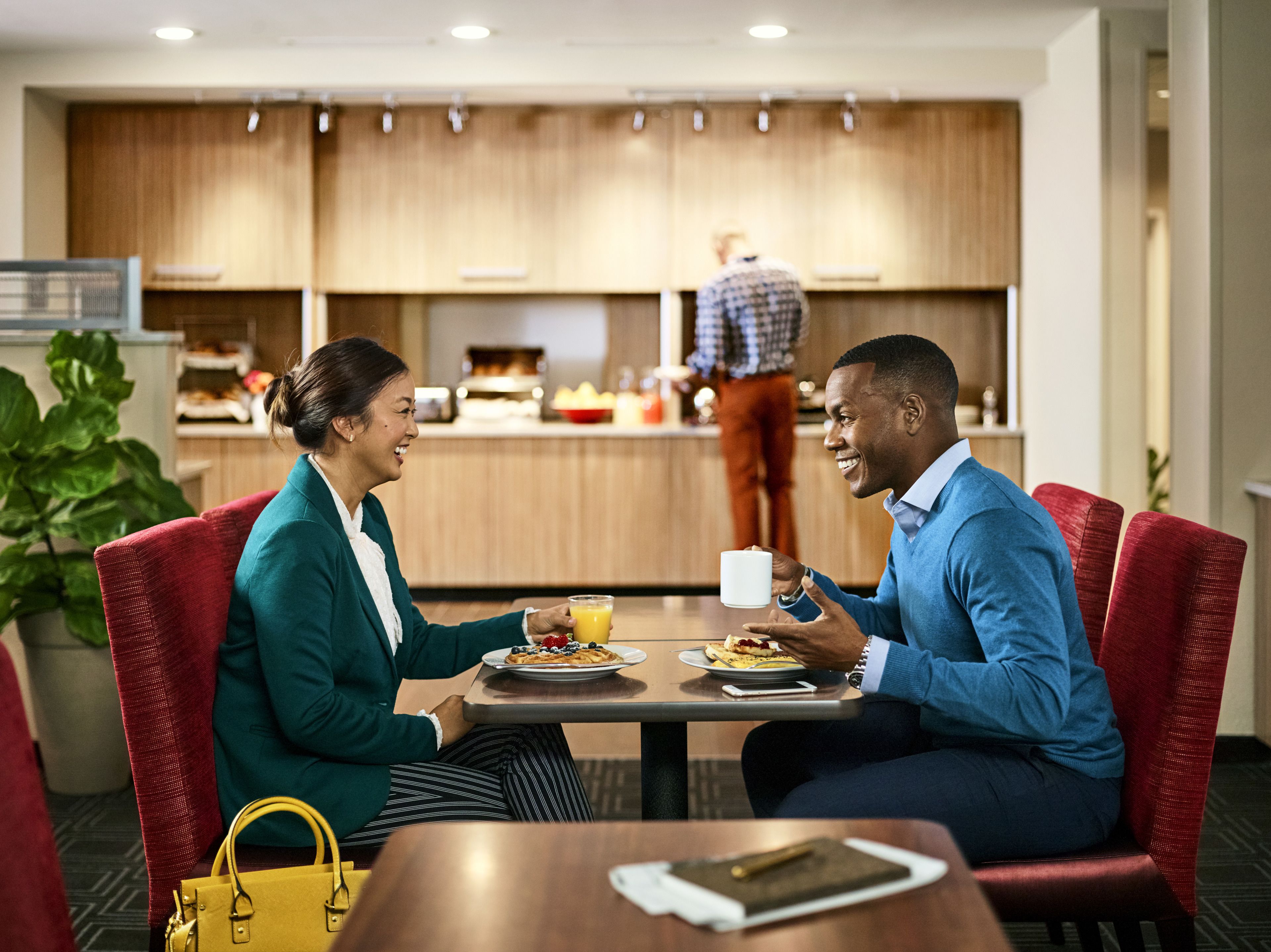 Una pareja cenando en un restaurante moderno de hotel, con vista a la cocina.