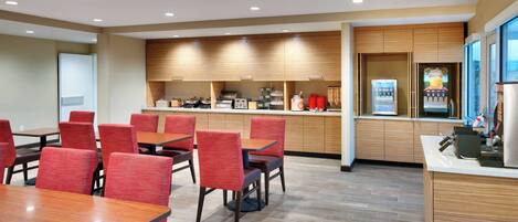 A modern dining area with wooden cabinets, red upholstered chairs, and a counter with a coffee machine.