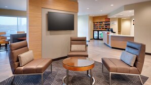 A modern lobby with leather sofas, a glass coffee table, a flat-screen TV, a reception desk, and a bookshelf. - TownePlace Suites by Marriott Salt Lake City Draper (Draper)