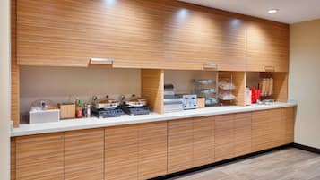A modern kitchen with wooden cabinets, a countertop with appliances, and a tiled floor.
