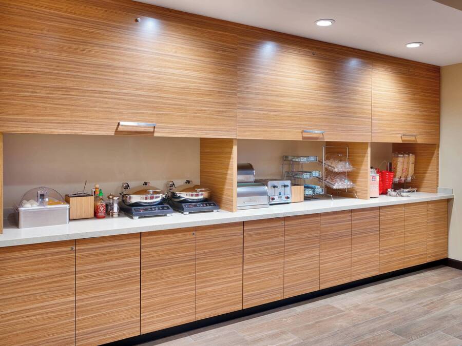 A modern kitchen with wooden cabinets, a countertop with appliances, and a tiled floor.