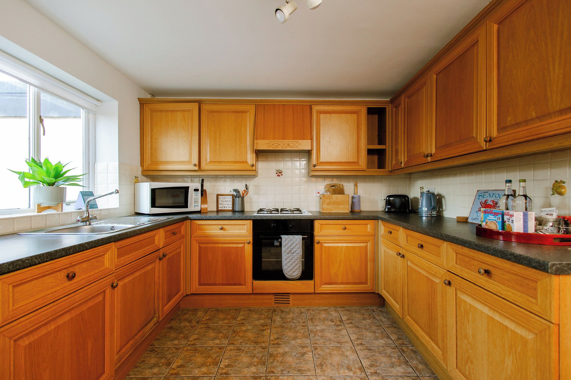 A kitchen with wooden cabinets, a microwave, a gas stove, and a sink.