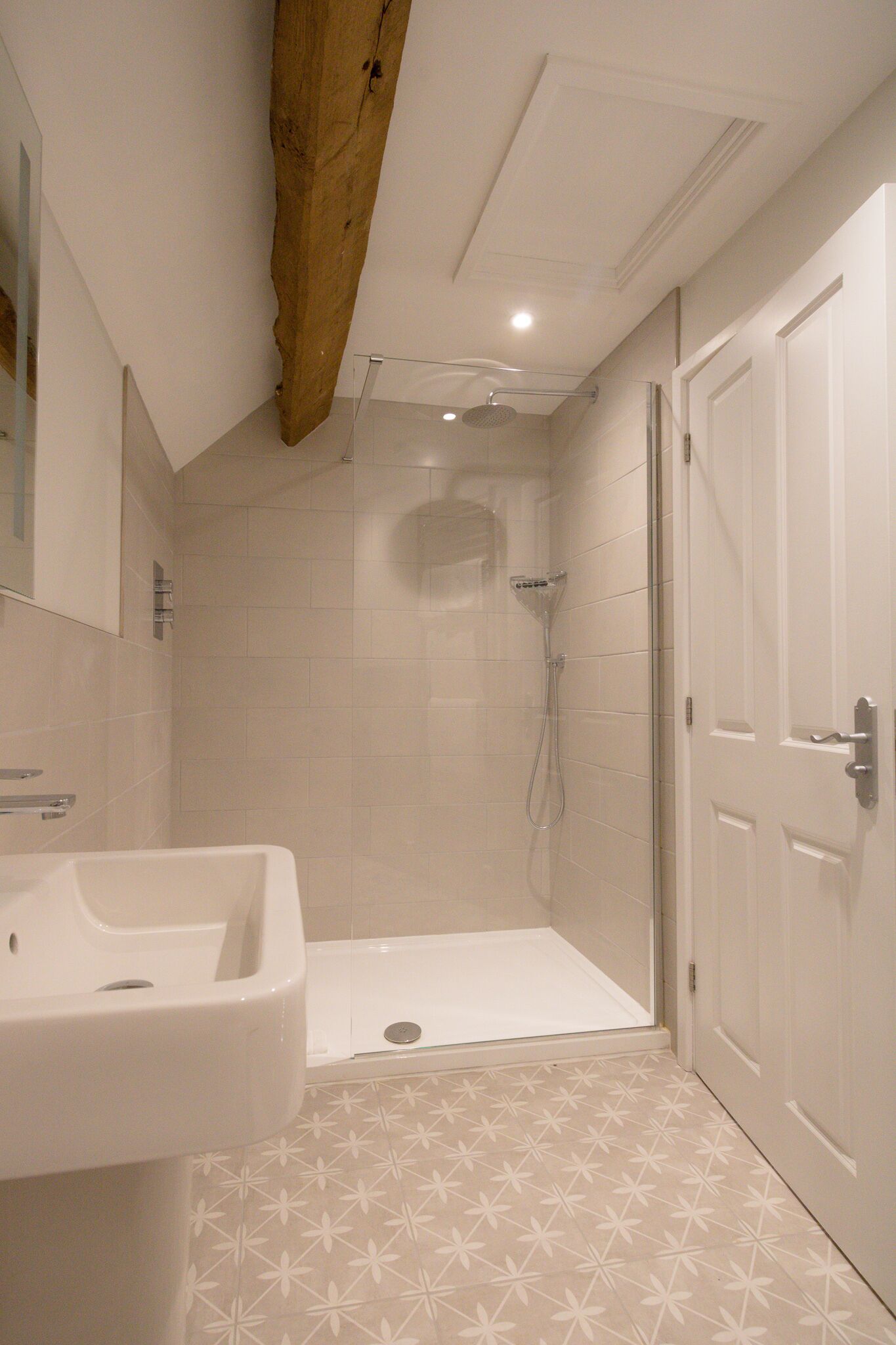A bathroom with a shower, a sink, and a door.