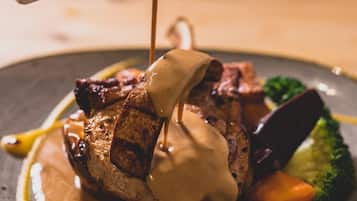 A plate of food with a steak, vegetables, and sauce.