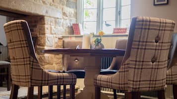 A dining area with a stone wall, a table, and four plaid chairs.