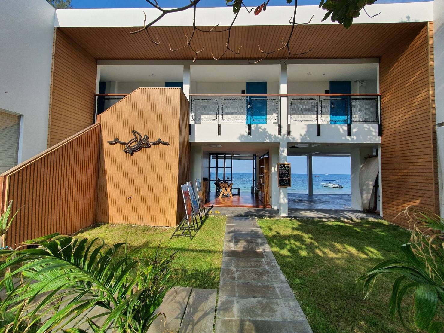 Een modern gebouw met een houten gevel, een balkon en uitzicht op zee.