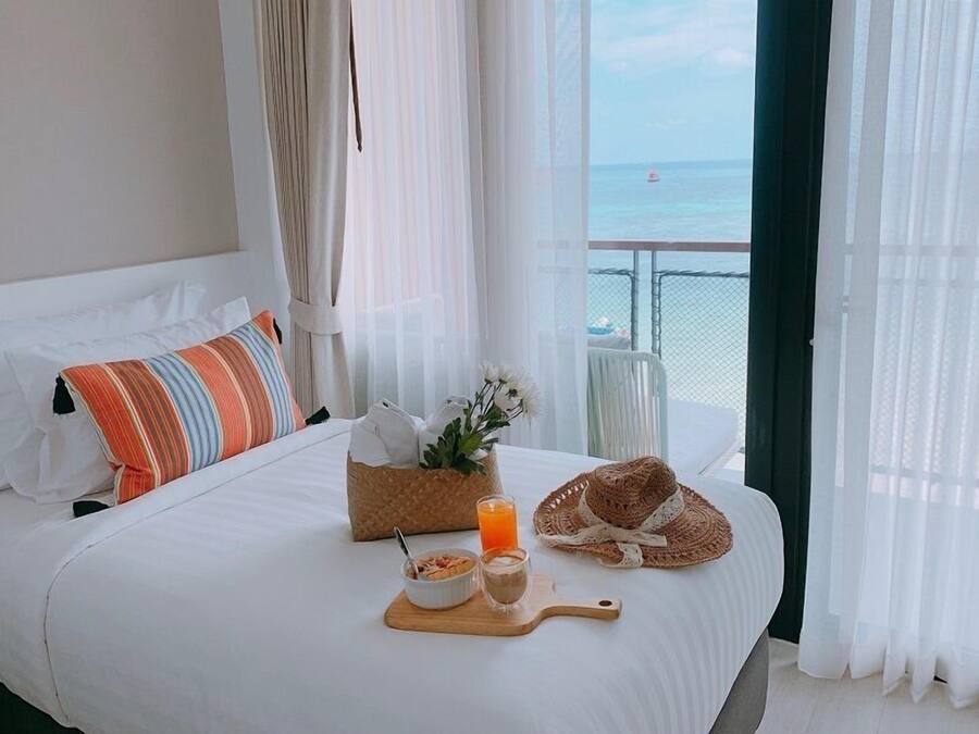 A hotel room with a bed, a breakfast tray with cereal, orange juice, and a croissant.
