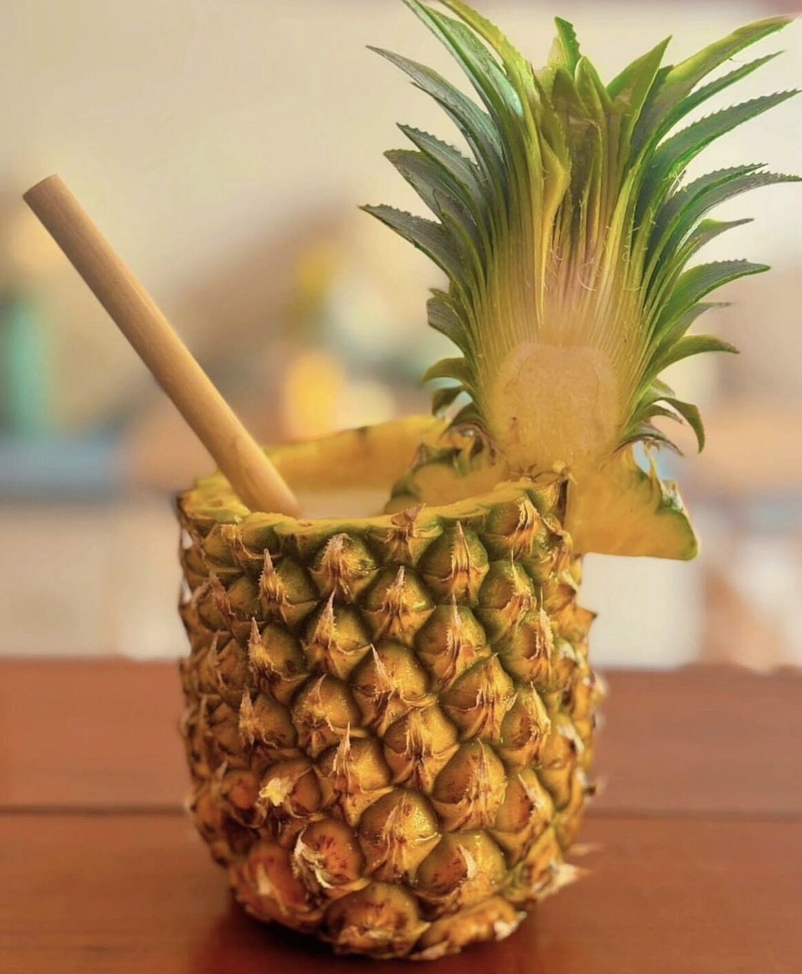 Un ananas avec un bâtonnet en bois inséré, posé sur une surface en bois.