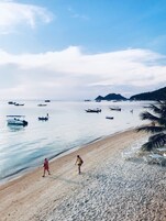 Una playa con barcos, una orilla arenosa y cielo despejado.