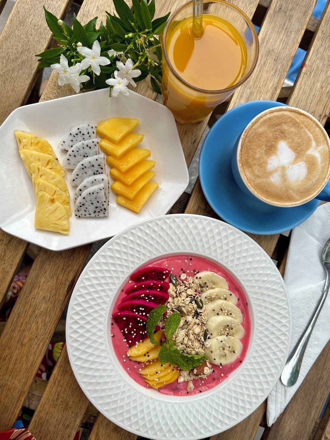 Una mesa con un plato de fruta, un batido y una taza de café.