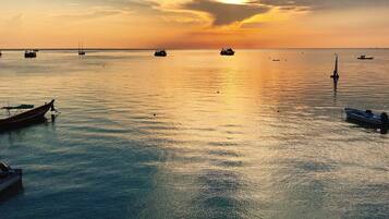 Mar tranquila con barcos al atardecer.