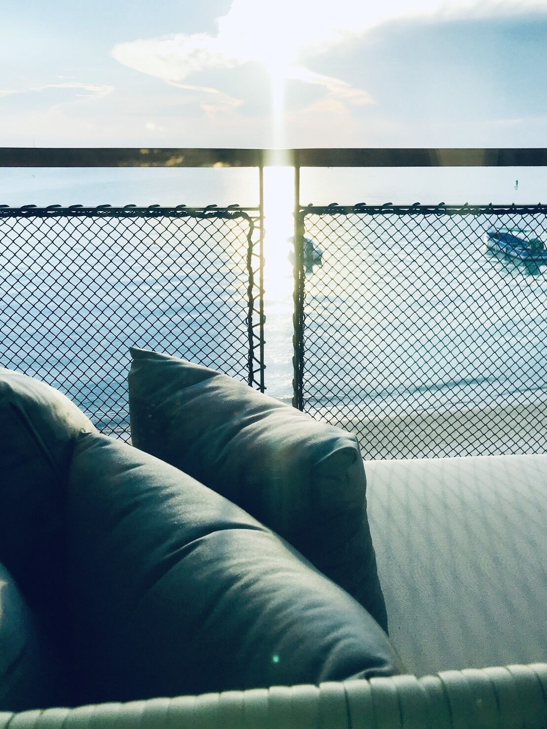 Een balkon met uitzicht op zee, voorzien van een metalen hekwerk en kussens.