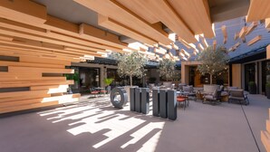 A modern outdoor seating area with wooden beams overhead and a concrete floor. - Omm Inn (Eskisehir)