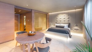 A modern bedroom with a bed, bedside table, and a round dining table with chairs. - Omm Inn (Eskisehir)