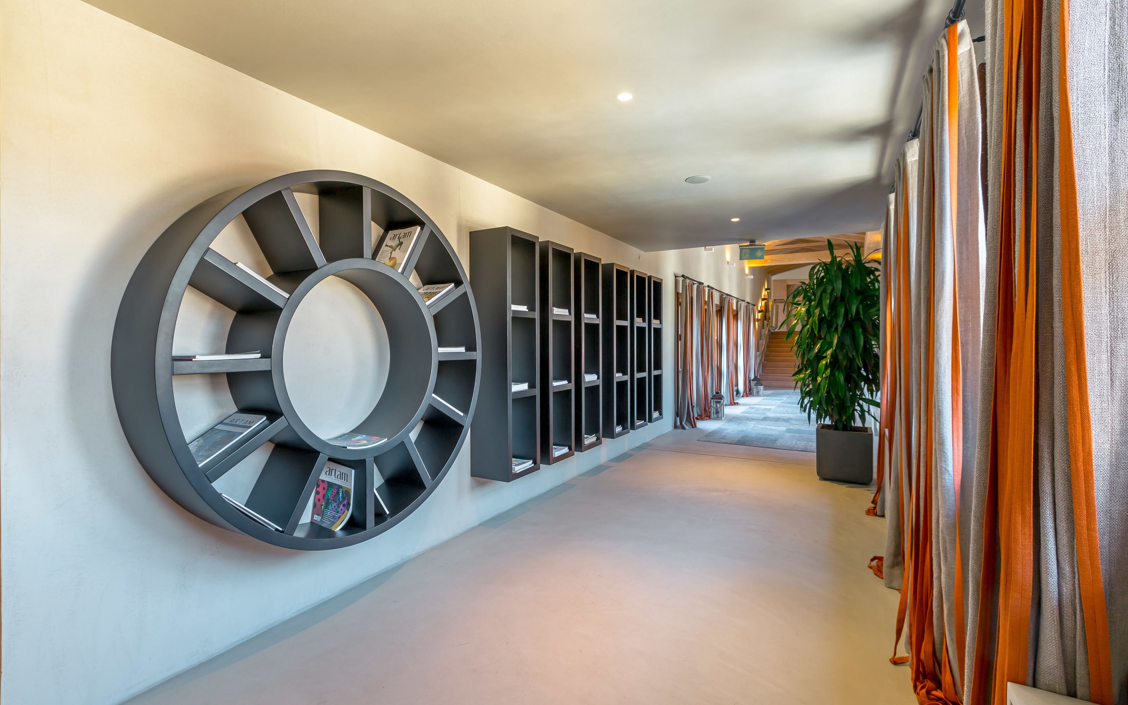 Een hal met een grote ronde wanddecoratie, een reeks boekenkasten en een trap op de achtergrond.