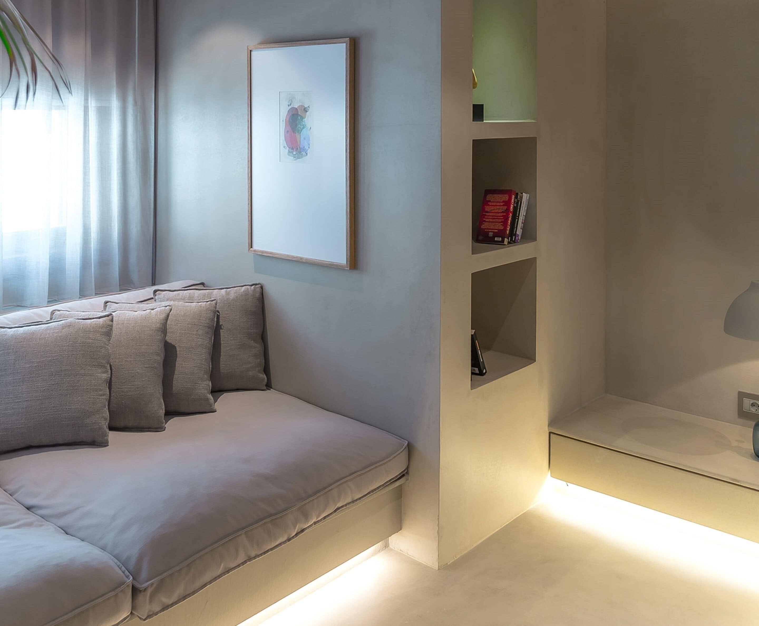 A modern living room with a sofa, a framed artwork, and built-in shelving with books.